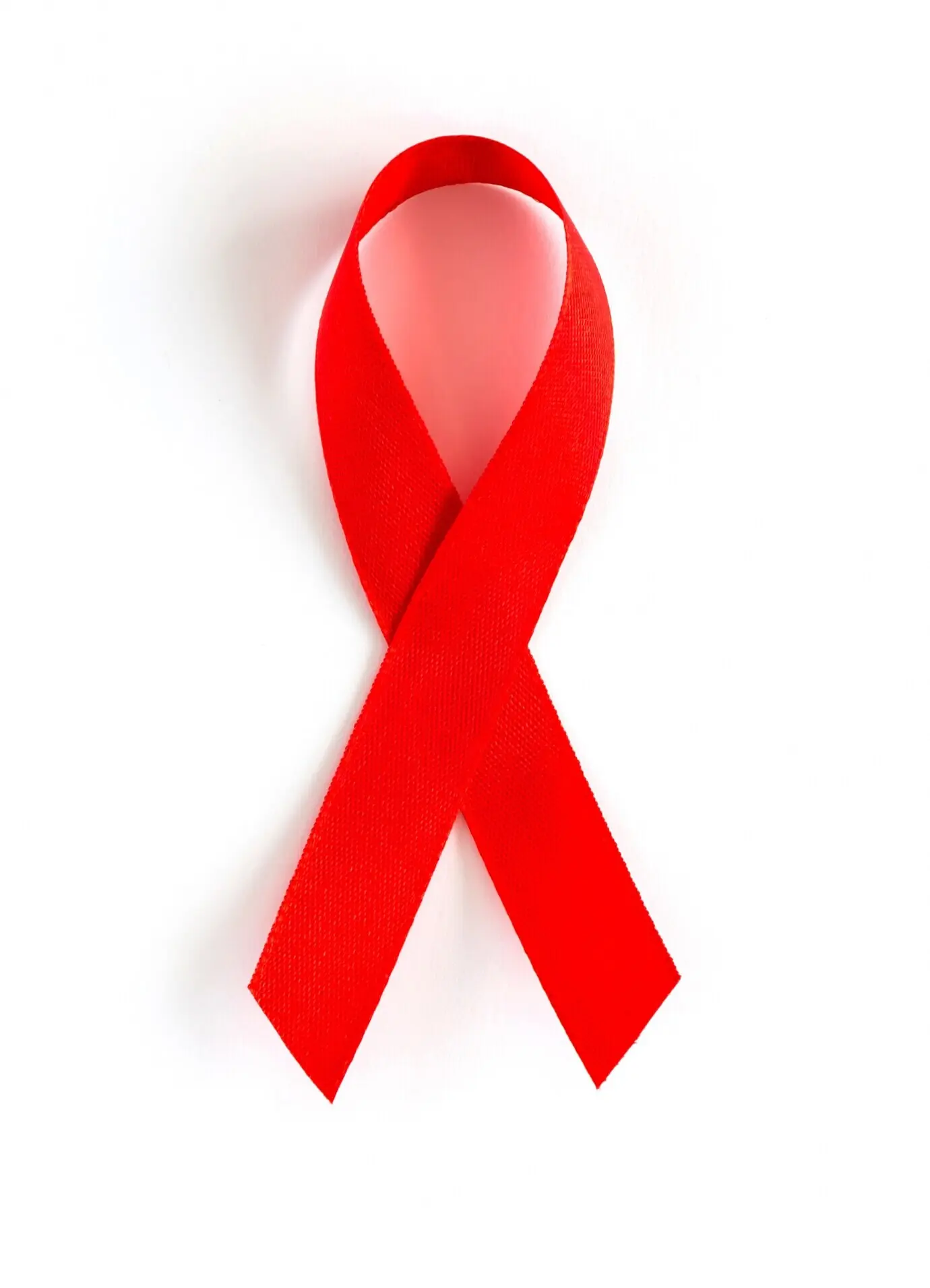 An AIDS awareness red heart ribbon, isolated on a white background.
